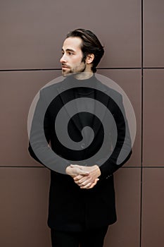 Successful businessman in formal stylish suit standing outside the office, looking at the side, posing for photography