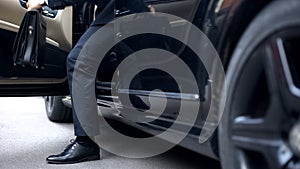 Successful businessman getting out of premium class car, arrival to workplace