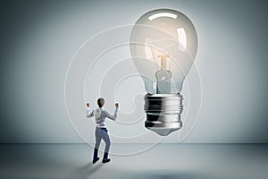 Successful businessman with glowing light bulb in concrete room. Success, idea and innovation concept
