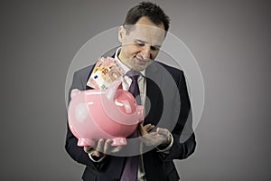 Successful businessman holds piggy bank with money europen banknotes in hands