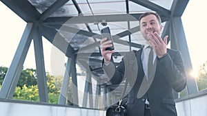 Successful businessman holds a smartphone, he communicates via video link. Joyful businessman