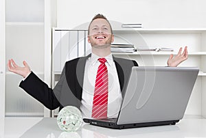 Successful businessman laughing with hands up and laptop