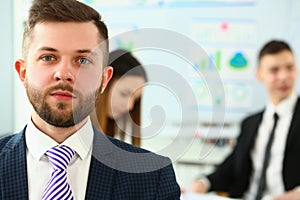 Successful businessman in presentable suit, colleagues on background, conference meeting