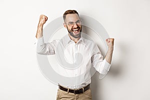 Successful businessman rejoicing, raising hands up and celebrating victory, winning something, standing over white