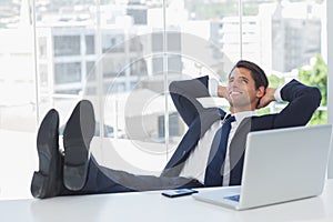 Successful businessman relaxing with his feet on his desk