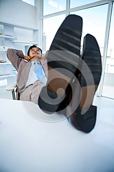 Successful businessman relaxing with his feet on his desk