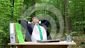 Successful businessman relaxing outdoors after hardworking, eco-friendly office
