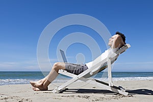 Successful businessman resting on a tropical beach with laptop