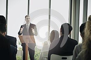 Successful businessman sharing experiences and giving a speech  group of business people sitting on conference together listening