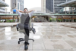 Successful businessman sitting on chair with relaxation on city blurred background