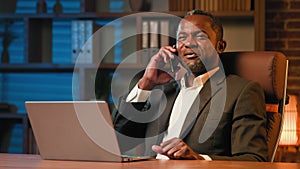 Successful businessman sitting in office talking to client on mobile phone at workplace african american man answering