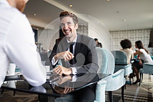 Successful businessman smiling while discussing with partner during meeting at coffee break