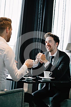 Successful businessman smiling while discussing with partner during meeting at coffee break