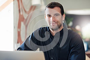 Successful businessman smiling and using a laptop in an office