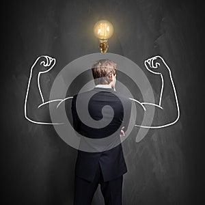 Successful businessman standing in front of a blackboard with a bright lightbulb over his head