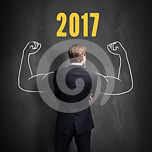 Successful businessman standing in front of a blackboard with 2017