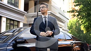 Successful businessman standing near luxury car, social welfare, life insurance
