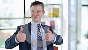 Successful businessman in suit showing thumbs up in office