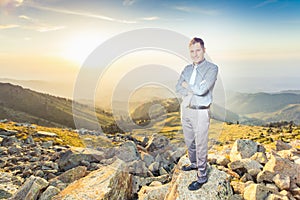 Successful businessman at top of mountain looking at camera
