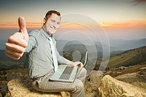 Successful businessman on top of mountain, using a laptop