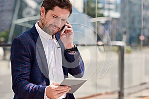 Successful businessman using a tablet and cellphone in the city