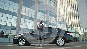 Successful businessman waiting car adjusting suit. Proud company owner posing