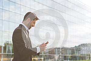 Successful businessman or worker standing in suit with cellphone