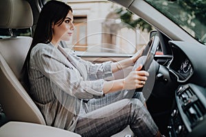 Successful businesswoman driving car through modern urban city