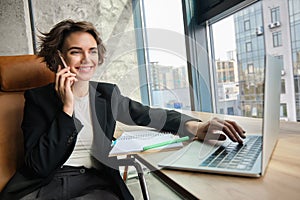 Successful businesswoman in office, having conversation over mobile phone, calling business partner, negotiating