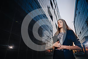 Successful businesswoman stands on the background of buildings and holding tablet computer. City business woman working.