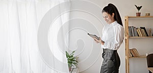 Successful businesswoman in stylish closes using tablet computer, standing in office working on business and marketing