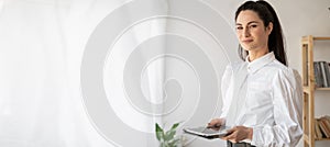 Successful businesswoman in stylish closes using tablet computer, standing in office working on business and marketing