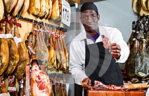 Successful butcher shop owner recommending to taste delicious iberian ham