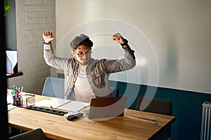 Successful caucasian businessman celebrating win in work and watching on laptop