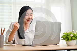 Successful and cheerful Asian female college student passing an online test