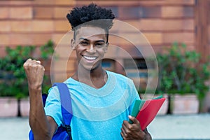 Successful cheering afro american male student with backpack and paperwork