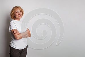 Successful confident middle age woman wearing casual t-shirt standing with crossed arms against white studio wall banner