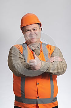 Successful construction worker in hard hat showing thumb up on grey studio background, happy fat engineer