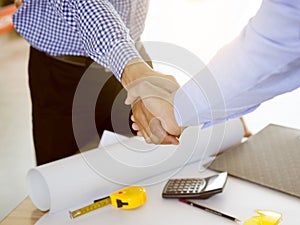 Successful deal, Female architect shaking hands with client in construction site after confirm blueprint for renovate building