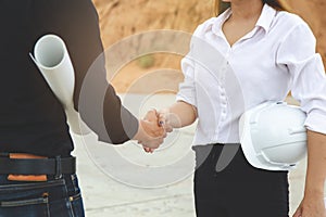 Successful deal, Female architect shaking hands with client in construction site after confirm blueprint for renovate building