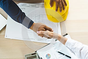 Successful deal, male architect shaking hands with client in construction site after confirm blueprint for renovate building
