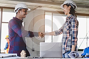 Successful deal, male architect shaking hands with client in construction site after confirm blueprint for renovate building