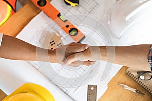 Successful deal, male architect shaking hands with client in construction site after confirm blueprint for renovate building