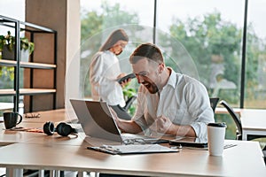 Successful deal. Using laptop. Man and woman are working in the modern office together