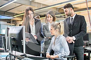 Successful diverse young business team working together on a project grouped around an office table in a teamwork.