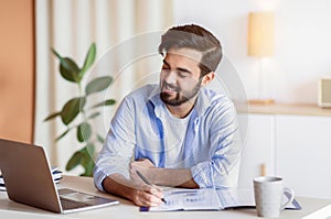 Successful Eastern Entrepreneur Working With Documents And Laptop At Home Office