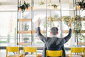 Successful excited business man happy smile hold fist gesture view from back, handsome young businessman with raised hands arms.