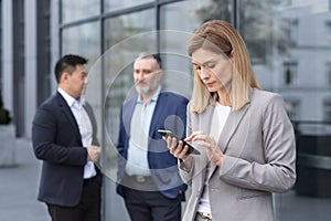 A successful and experienced business woman outside the office building is reading from a tablet computer