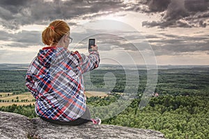 Successful female hiker takes photo at edge