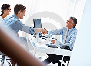 Successful financial plans. Mature male advisor shaking hands with handsome man and woman in office.